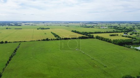 Rural farmland to horizontal lines in Fairland, Oklahoma, center pivot irrigation water energy-efficient with pipeline mobile truss structures motorized wheels move through field, aerial view. USA