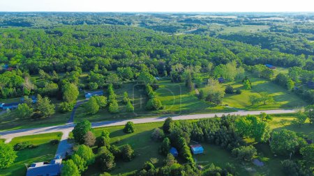 Country road US-60 BUS in rural Mountain Grove Missouri through lush greenery trees acreage, meadows and farm houses with ponds in agricultural area, peaceful countryside in Midwest, aerial view. USA