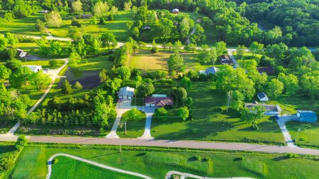 Golf course country club in rural area with low density housing, lush greenery trees large acreage, meadows and farm houses near back road in agricultural area, peaceful Midwest, aerial view. USA