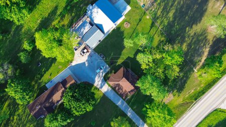 Direct aerial view farm houses with long driveway, large storage sheds, acreage lots, lush greenery trees in countryside Mountain Grove Missouri, peaceful rural agricultural area in Midwest. USA