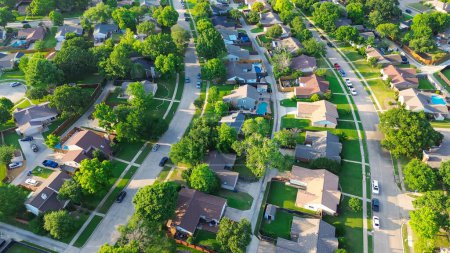 Parallel residential streets with back alleys and row of single-family houses surrounding by lush green trees in suburbs Dallas Fort Worth metro complex, suburban homes swimming pool, aerial. USA