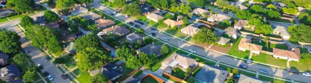 Panorama aerial view parallel residential streets with back alleys and row of single-family houses surrounding by tall lush green trees in suburbs Dallas Fort Worth metro complex, swimming pool. USA