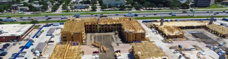 Panorama aerial view apartment under construction, Interstate I-35E Stemmons Freeway downtown Dallas, timber wood frame, elevator vertical shaft, large courtyard, slab foundation, heavy equipment. USA