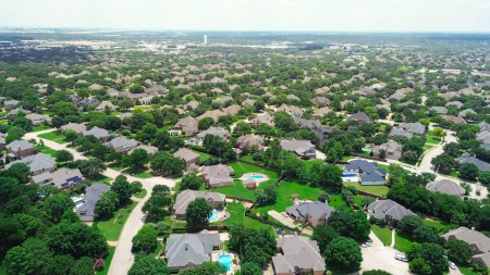Urban sprawl with row of upscale two-story suburban home in large lot backyard, local pond with water fountain in master planned community water tower in distant background, Southlake, Texas. USA