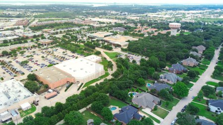 Downtown Southlake Texas mixed use development with large shopping center busy parking lot, residential neighborhood upscale houses swimming pool, municipal area with water tower, aerial view. USA