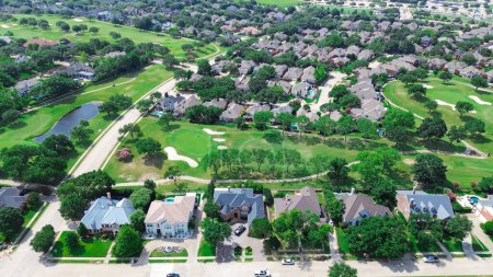 Luxury two story houses with swimming pool near golf course in East of Plano, Texas, Dallas Fort Worth metroplex, upscale large mansion homes fenced backyard, lush greenery tree, aerial view. USA
