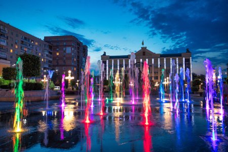 Téléchargez les photos : The central square of the city of Irpin. The fountain is illuminated with colors. A wonderful warm summer evening, miss - en image libre de droit