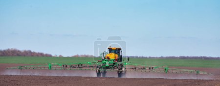 Photo for Soil treatment with drugs. Application of herbicides. pesticides or fertilizers with the help of a tractor. - Royalty Free Image