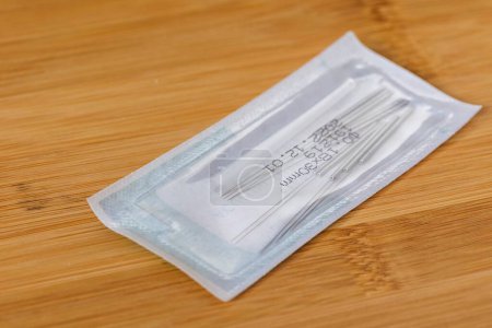 Photo for A close up portrait of one package full of tin long acupuncture needles, ready to use on someone with health issues. There is also a plastic tube inside in order to assist the acupuncturist. - Royalty Free Image