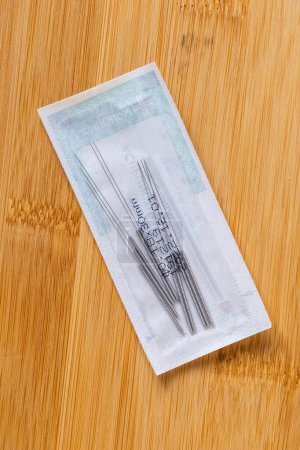Photo for A top down portrait of one package full of tin long acupuncture needles, ready to use on someone with health issues. There is also a plastic tube inside in order to assist the acupuncturist. - Royalty Free Image