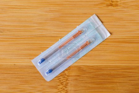 Photo for A closeup portrait of tin acupuncture needles with a copper handle still in the package, ready to use on someone with health issues. There is also a tube inside in order to assist the acupuncturist. - Royalty Free Image