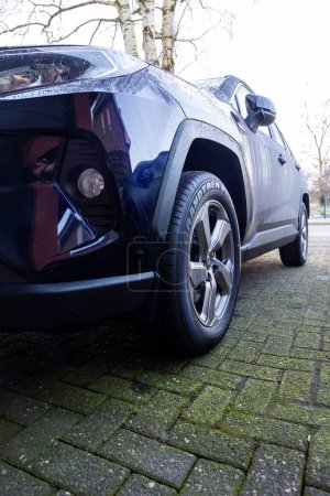 Brecht, Bélgica - 21 de enero de 2022: Un retrato del faro derecho de un coche híbrido azul oscuro toyota rav4 estacionado en un camino de entrada. El vehículo puede conducir eléctricamente y con combustibles fósiles.