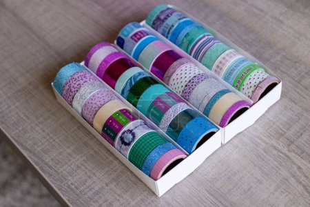 Foto de Un retrato de una caja llena de rollos coloridos de cinta washi con diferentes colores, patrones y texturas. Las cintas están listas para ser utilizadas para decorar un interior, regalo o postal, regalo. - Imagen libre de derechos