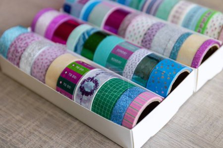 Foto de Un retrato de una caja llena de rollos coloridos de cinta washi con diferentes colores, patrones y texturas. Las cintas están listas para ser utilizadas para decorar un interior, poste o tarjeta de regalo, regalo. - Imagen libre de derechos