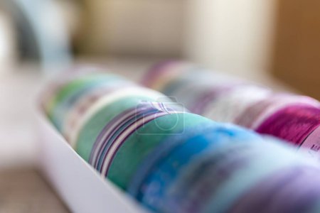 Foto de Un primer plano de cinta washi colorido en diferentes patrones y colores en una caja. Los rollos decorativos están listos para usar para decorar una tarjeta de regalo, regalo o postal o para usar para el diseño de interiores como en una pared.. - Imagen libre de derechos