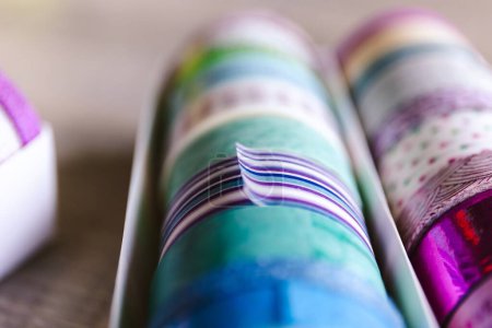 Foto de Cinta washi colorida en diferentes patrones y colores en una caja. Los rollos decorativos están listos para usar para el diseño de interiores como en una pared o para decorar un regalo, poste o tarjeta de regalo o para que algunos los usen.. - Imagen libre de derechos