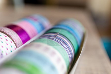 Foto de Un retrato de cinta washi colorida en diferentes patrones y colores en una caja. Los rollos decorativos están listos para usar para decorar una tarjeta de regalo o postal, regalo o para usar para el diseño de interiores como en una pared.. - Imagen libre de derechos