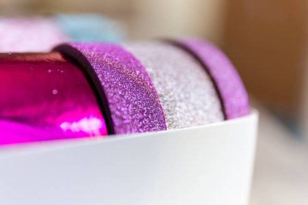 Foto de Un retrato de unos rollos de cinta washi en una caja. Las cintas decorativas son de color rosa y púrpura y tienen brillo en ellas, listas para decorar un regalo, interior, pared, poste o tarjeta de regalo.. - Imagen libre de derechos