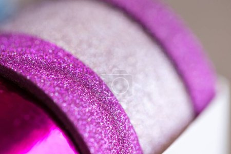 Foto de Un macroretrato de unos rollos de cinta washi en una caja. Las cintas decorativas son de color rosa y púrpura y tienen brillo en ellas, listas para decorar un regalo, interior, pared, poste o tarjeta de regalo.. - Imagen libre de derechos