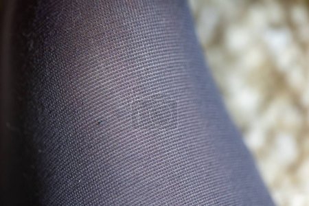 Foto de Un retrato de cerca de la tela y la textura de la tela o material de pantimedias de nylon negro, medias, medias o medias que recubren una pierna. Los hilos están haciendo un patrón de rectángulo. - Imagen libre de derechos
