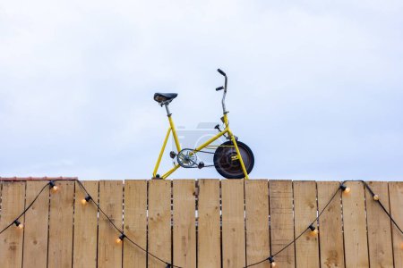 Photo for A front portrait of an old vintage home trainer or bike standing on top of a building with wooden planks as the front. This could be the top of a gym or sport store. - Royalty Free Image