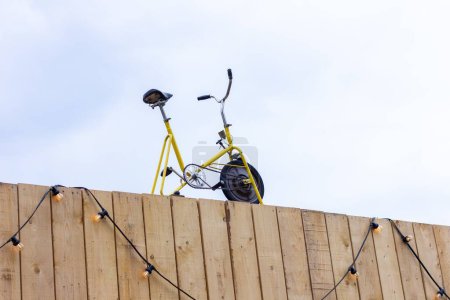 Photo for A close up portrait of an old vintage home trainer or bike standing on top of a building with wooden planks as the front. This could be the top of a gym or sport store. - Royalty Free Image