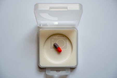 Foto de Una cápsula se coloca en una caja cuadrada, espalda blanca. - Imagen libre de derechos