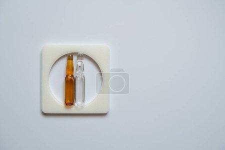 Photo for Two ampoules, clear and brown, placed in a square frame, with a white back. - Royalty Free Image