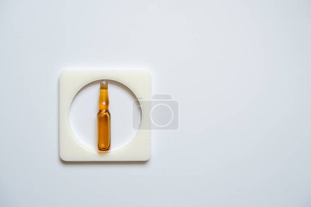 One ampoule is brown, enclosed in a square frame, with a white back.