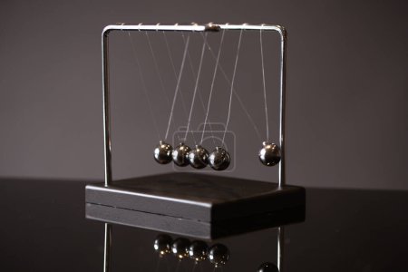Téléchargez les photos : Berceau Newton en métal serré placé sur fond gris comme représentation du concept de momentum - en image libre de droit