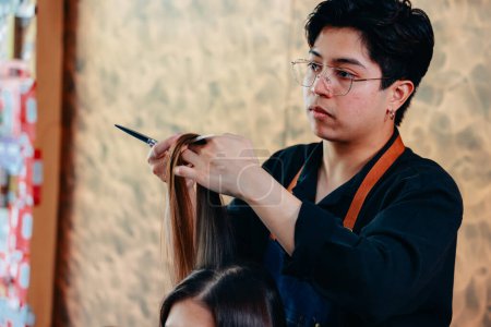 Téléchargez les photos : Jeune homme asiatique coiffeur se concentrant sur le travail tout en coupant et en coupant les cheveux longs et beaux de la cliente dans le salon moderne - en image libre de droit