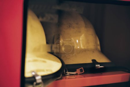 Foto de Trajes de bombero y cascos colgados en un vestuario en la estación de bomberos - Imagen libre de derechos