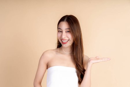 Foto de Retrato de cerca de una cara de una joven asiática con una piel facial saludable. Hermosa mujer que presenta un espacio vacío en la palma de su mano - utilizado para promover y anunciar productos en el fondo del estudio - Imagen libre de derechos