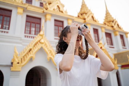 Photo for Asian woman tourist backpacker smiling, traveling and taking photo with temple background in Bangkok, Thailand. Asian people excited and having fun traveling. - Royalty Free Image
