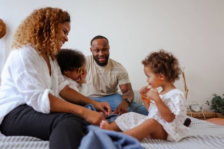Téléchargez les photos : Bonne famille noire sur un lit jouer, coller, avoir du plaisir de qualité. amour et enfants africains souriant avec les parents dans la chambre à coucher avec amour bonheur, détente et soulagement du stress - en image libre de droit