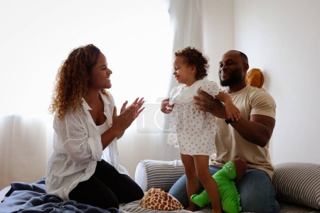Photo for Happy black family on a bed playing, bonding, having quality fun time. love and African daughter smiling with parents in the bedroom with love happiness, relaxation and stress relief - Royalty Free Image
