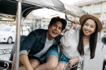 Téléchargez les photos : Joyeux et joyeux jeune couple asiatique touristes en tuk tuk tour, rickshaw style transport dans la rue à Bangkok en Thaïlande les gens qui voyagent en appréciant le concept de culture locale - en image libre de droit