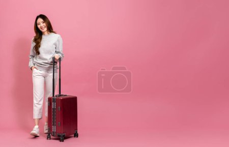 Photo for Beautiful asian female passenger in sweater, jeans, and luggage. Portrait of a smiling girl with luggage in full length size. Winter lifestyle and travel concept - Royalty Free Image