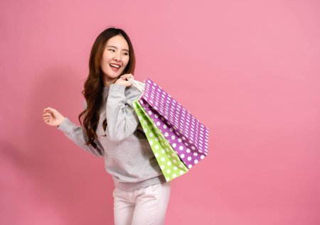 Foto de Retrato de una joven asiática feliz compradora sonriente sosteniendo bolsas de compras en fondo rosa - Concepto de mujer de compras en línea - Imagen libre de derechos