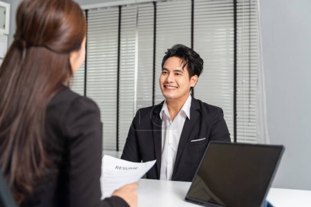 Photo for Asian male business job applicant being recruited by a young adult business female employer on desk in company office while having a computer laptop with her. Career recruitment concept - Royalty Free Image