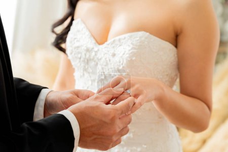 Téléchargez les photos : Gros plan du marié plaçant une bague en diamant sur le doigt de la mariée, symbolisant l'amour éternel et l'engagement concept de cérémonie de mariage - en image libre de droit