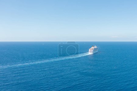 Photo for Cruise ship liner sails in the blue sea leaving a plume on the surface of the water seascape. Aerial view The concept of sea travel, cruises - Royalty Free Image