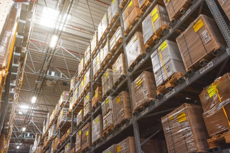 Photo for Retail warehouse full of shelves with goods in wooden crates, boxes and packages. Logistics, sorting and distribution for product delivery. Look up, light - Royalty Free Image