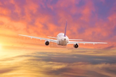 Téléchargez les photos : L'avion vole au loin le ciel couchant est magnifiquement éclairé - en image libre de droit