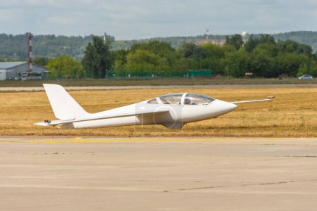 Ultralight glider plane stands on the grass, landing on earth aerodrome