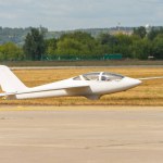 Ultralight glider plane stands on the grass, landing on earth aerodrome