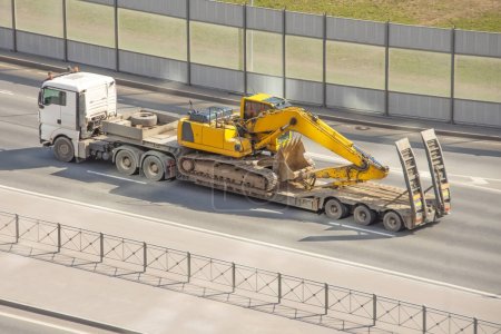 Photo for Excavator loaded on a trailer for heavy equipment. heavy transport truck. - Royalty Free Image