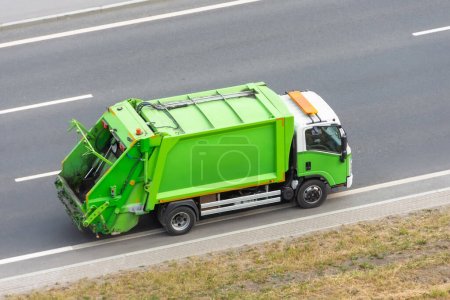 Recycling green truck rides on the road in the city