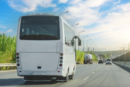 White Moderner komfortabler Touristenbus, der bei strahlendem Sonnenschein durch die Autobahn fährt. Reise- und Bustourismuskonzept. Reise und Anreise mit dem Fahrzeug