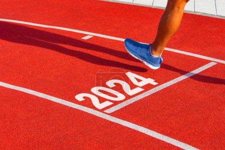 Runner cruza la línea de meta en una cinta de correr roja con los números 2024. Año nuevo concepto de entrada, paso